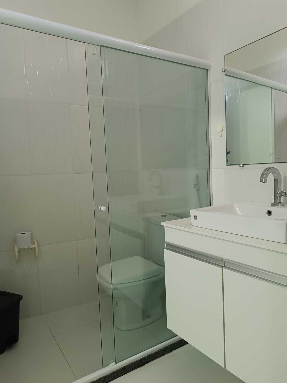 A bathroom with a glass shower enclosure, a white sink, and a mirror above it.