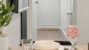 A dining area with a table set for four, including plates, cutlery, and a glass with a heart pattern. - London 3 Bedroom Cosy Clean Home Sleeps 6 Stratford Excel Modern (London)