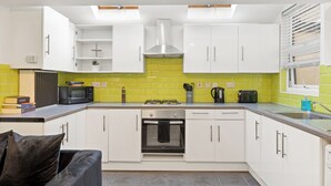 A modern kitchen with white cabinets, a built-in oven, a microwave, and a gas stove. - London 3 Bedroom Cosy Clean Home Sleeps 6 Stratford Excel Modern (London)