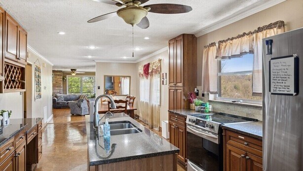 A spacious kitchen with wooden cabinets, a central island, a stainless steel refrigerator, and a ceiling fan. - 3 Bedroom Mid Century Brick Ranch Upstairs Home Near Smokies (Sevierville)