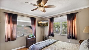 A bedroom with a bed, a ceiling fan, a TV, and windows with curtains. - 3 Bedroom Mid Century Brick Ranch Upstairs Home Near Smokies (Sevierville)