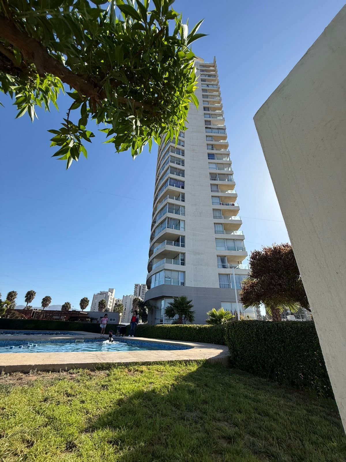 A tall, modern building with a pool area in the foreground.