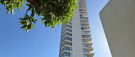 A tall, modern building with a pool area in the foreground.