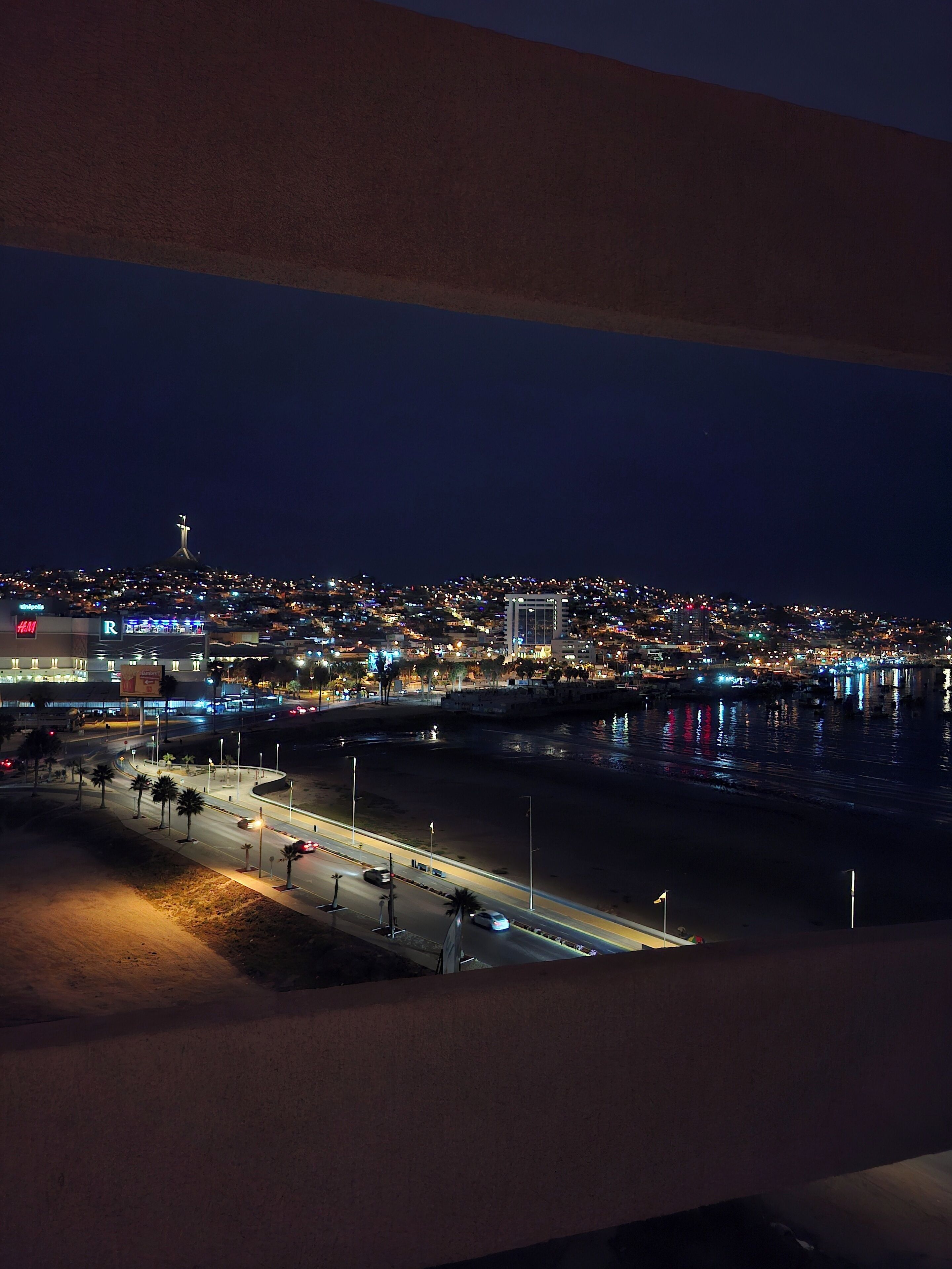 A nighttime cityscape with a river, illuminated buildings, and a prominent tower.