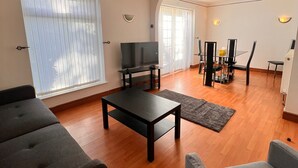 Un salon spacieux équipé d’un téléviseur à écran plat, de deux canapés, d’une table basse et d’un coin repas avec une table et des chaises.