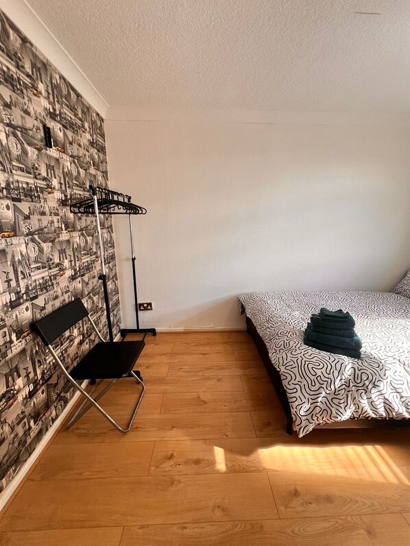 A room with a bed, a chair, a wall-mounted rack, and a patterned wall. - Stylish home to rent 100 meters from the Eithad stadium and Coop Live arena (Manchester)