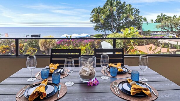 Mesa para dos con vista despejada al océano y vegetación tropical.
