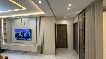 Una sala moderna con un televisor de pantalla plana en la pared, piso de mármol y estanterías empotradas.