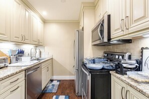 Uma cozinha moderna com armários brancos, eletrodomésticos de aço inoxidável e bancadas de granito.
