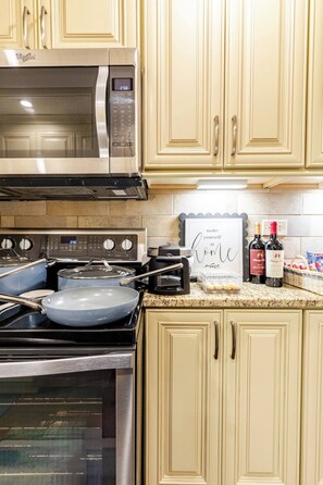 A kitchen with a microwave, stove, and oven. There are two wine bottles and a framed sign on the counter. - Downtown Walk | 2 Suites | Free Parking (Atlanta)