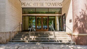 The entrance to Peachtree Towers with a glass door, metal handrails, and a set of stone steps leading up to the entrance.