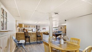 Un comedor espacioso con una mesa y sillas de madera, una cocina al fondo y una silla accesible para sillas de ruedas.