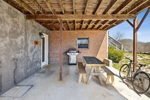 Un patio al aire libre con una parrilla, bancos de madera y una bicicleta.