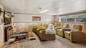 Una habitación con paredes de madera, un ventanal grande y un conjunto de sofás.
