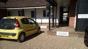 Un'auto gialla parcheggiata di fronte a un edificio con cartelli che indicano posti riservati a Wherry Cottage e Albion Cottage.