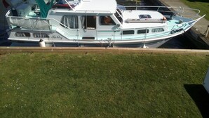 Una barca ormeggiata in una marina, con una zona di copertura, una cabina e un piccolo motore fuoribordo.