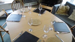 Un tavolo da pranzo rotondo apparecchiato per sei persone, con sottopiatti, posate e bicchieri da vino.