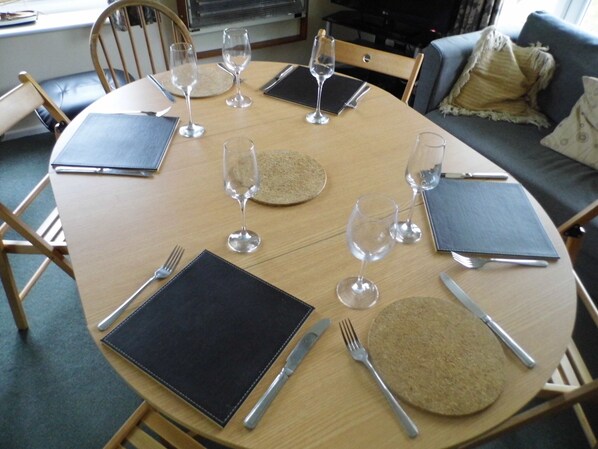 A round dining table set for six with placemats, cutlery, and wine glasses. - Pet-friendly riverside cottage, Wroxham, Norfolk, ideal for fishing / boating (Wroxham)