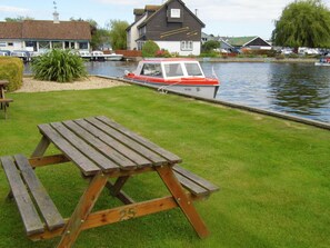 A picnic table with a number 25 on it, a boat with the number X155 on the water, and houses in the background. - Pet-friendly riverside cottage, Wroxham, Norfolk, ideal for fishing / boating (Wroxham)