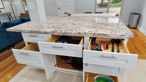 Eine Küche mit einer Granit-Arbeitsplatte, weißen Schränken und einer eingebauten Schublade mit Besteck.