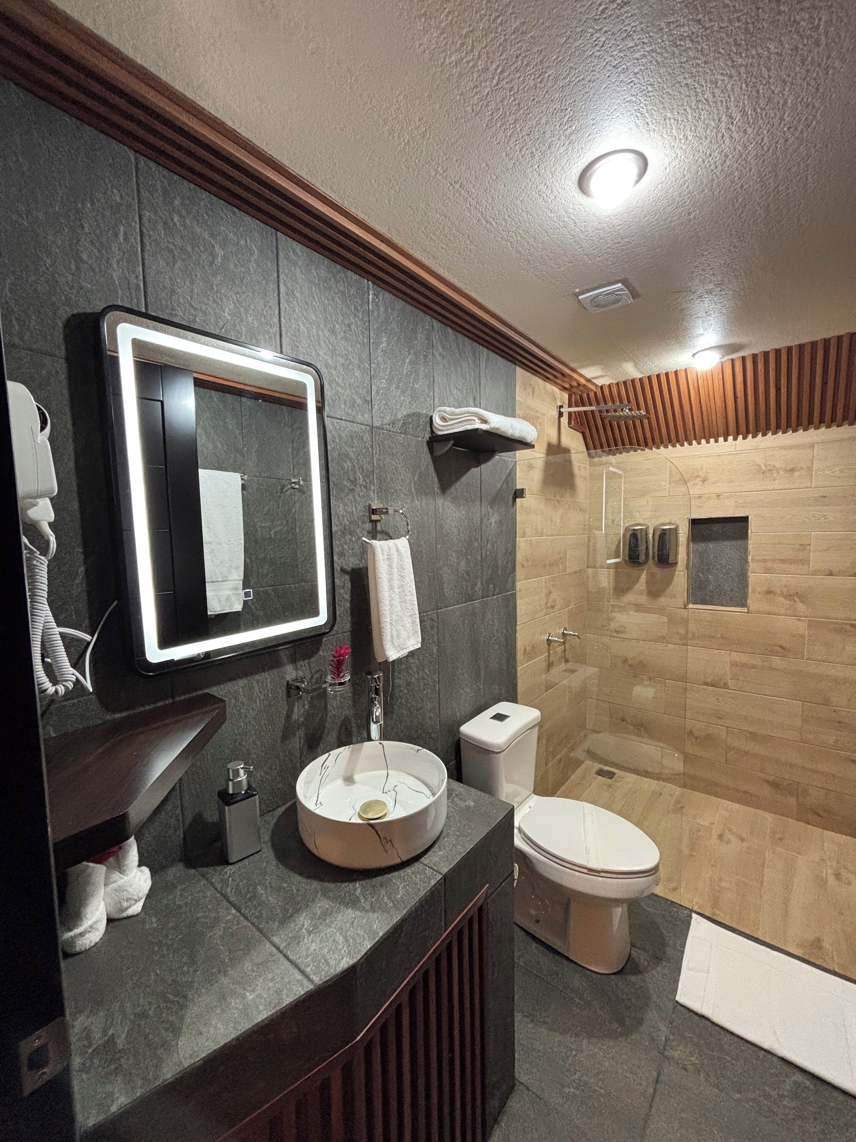 Un bagno moderno con un lavabo in marmo, un WC e una cabina doccia.