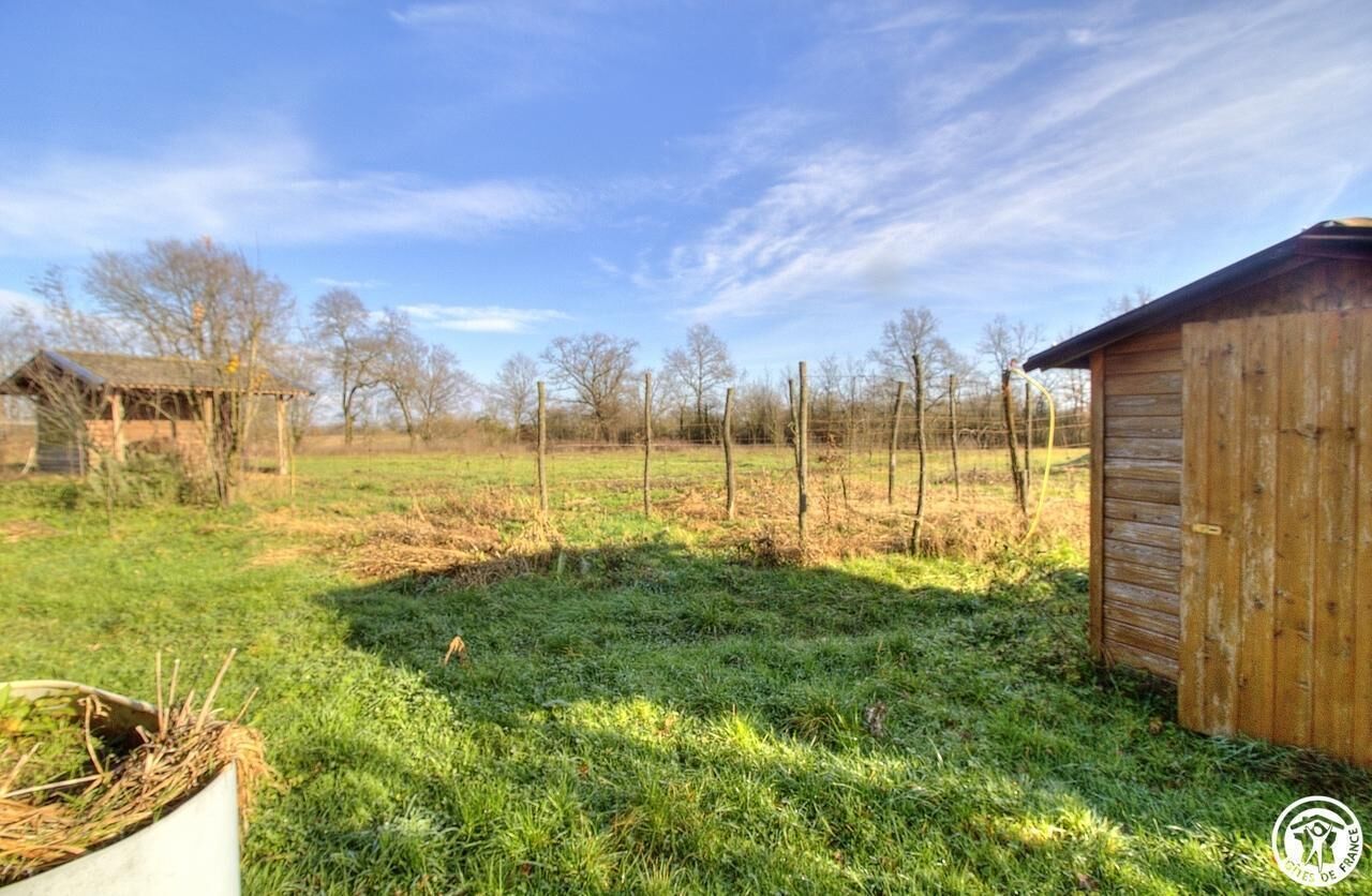 A rustic wooden shed in a grassy field with a clear sky.
