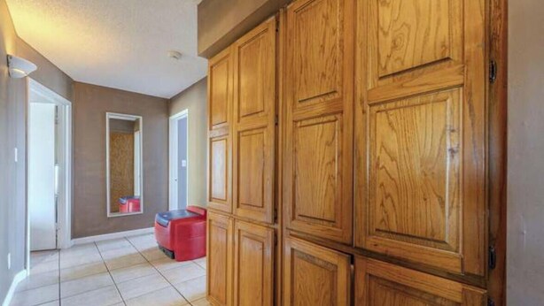 A hallway with wooden cabinets, a red trash bin, and a tiled floor. - Cozy 1-bedroom house in awesome Mesa with cool AC (Mesa)