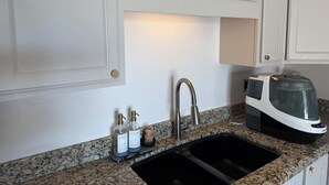 A kitchen with white cabinetry, a granite countertop, a black sink, a modern toaster, and two bottles of dish soap. - Cozy 1-bedroom house in awesome Mesa with cool AC (Mesa)