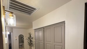 A hallway with a tiled floor, a dog lying on the floor, a vent on the ceiling, and a door with a light switch. - Cozy 1-bedroom house in awesome Mesa with cool AC (Mesa)