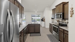 Een moderne keuken met roestvrijstalen apparatuur, donkere houten kastjes en een groot eiland.