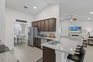 A modern kitchen with granite countertops, stainless steel appliances, and dark wooden cabinets. - Modern 4BR Retreat Near Beach Heated Pool (Palm Coast)