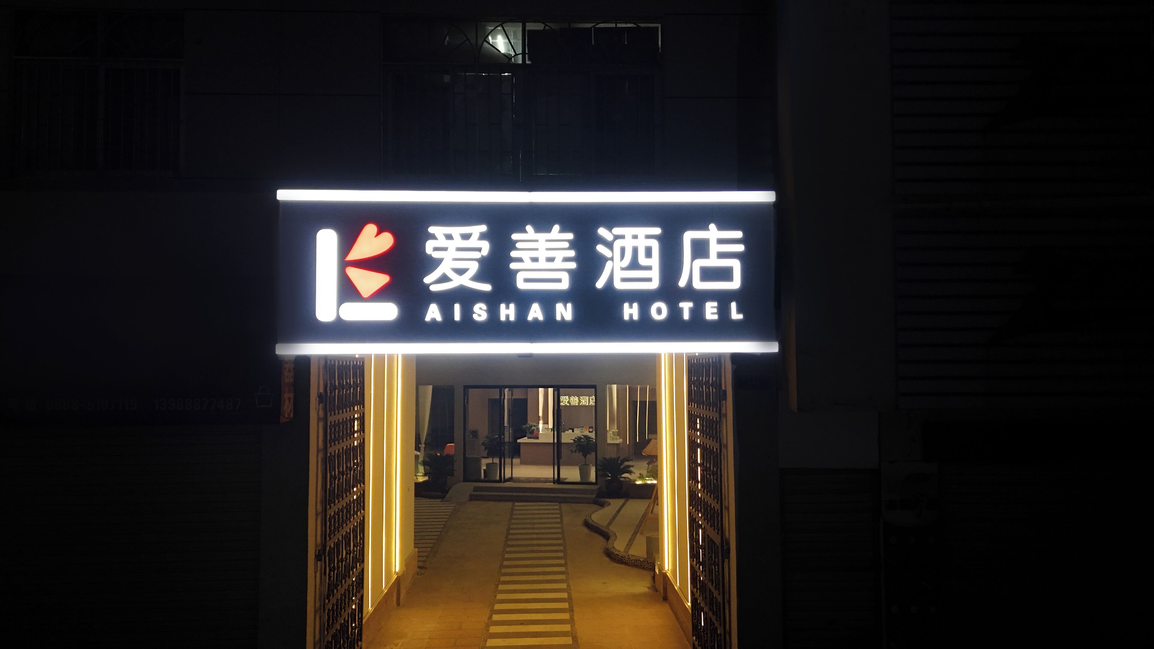 La entrada del Hotel Aishan, con un letrero y un camino que conduce al interior.