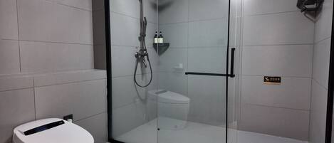 A modern bathroom with a glass-enclosed shower, a toilet, and a sink.