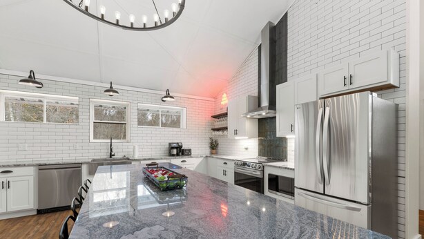 Una cocina moderna con paredes de ladrillo blanco, electrodomésticos de acero inoxidable y una isla de granito.