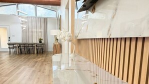 A modern reception desk with a marble countertop and a gold decorative element. - Luxury house with heated pool+Movie theatre room next to sixflags and la cantera (San Antonio)