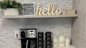 A kitchen counter with a coffee maker, mugs, and a sign saying "hello". - Luxury house with heated pool+Movie theatre room next to sixflags and la cantera (San Antonio)