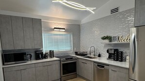 A modern kitchen with grey cabinets, stainless steel appliances, a wooden floor, and a 'hello' sign on the wall. - Luxury house with heated pool+Movie theatre room next to sixflags and la cantera (San Antonio)
