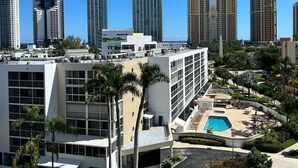 Un edificio alto con piscina en la azotea y palmeras.