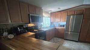 Cocina con armarios de madera, un refrigerador de acero inoxidable y encimera de madera.
