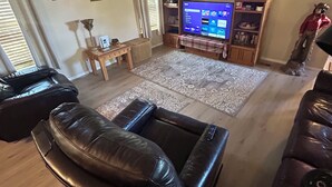 Una sala de estar con un sofá de cuero, un televisor y un ventilador de techo.