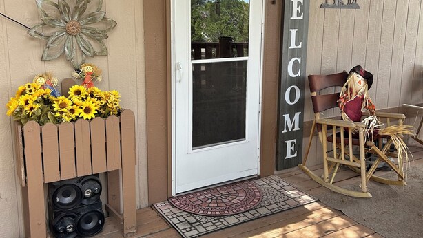 Una puerta de madera con un letrero de 'Welcome', un buzón y un arreglo floral.