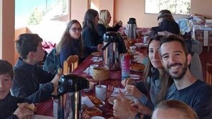 Een groep mensen dineert in een ruimte met een hoge plafond en grote ramen.