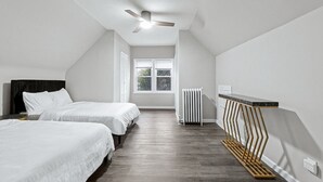 A bedroom with two beds, a ceiling fan, a radiator, and a window with a view of greenery. - Duplex|4Min Walk to NYC Train|Gameroom|Hotub+Sauna (Bayonne)