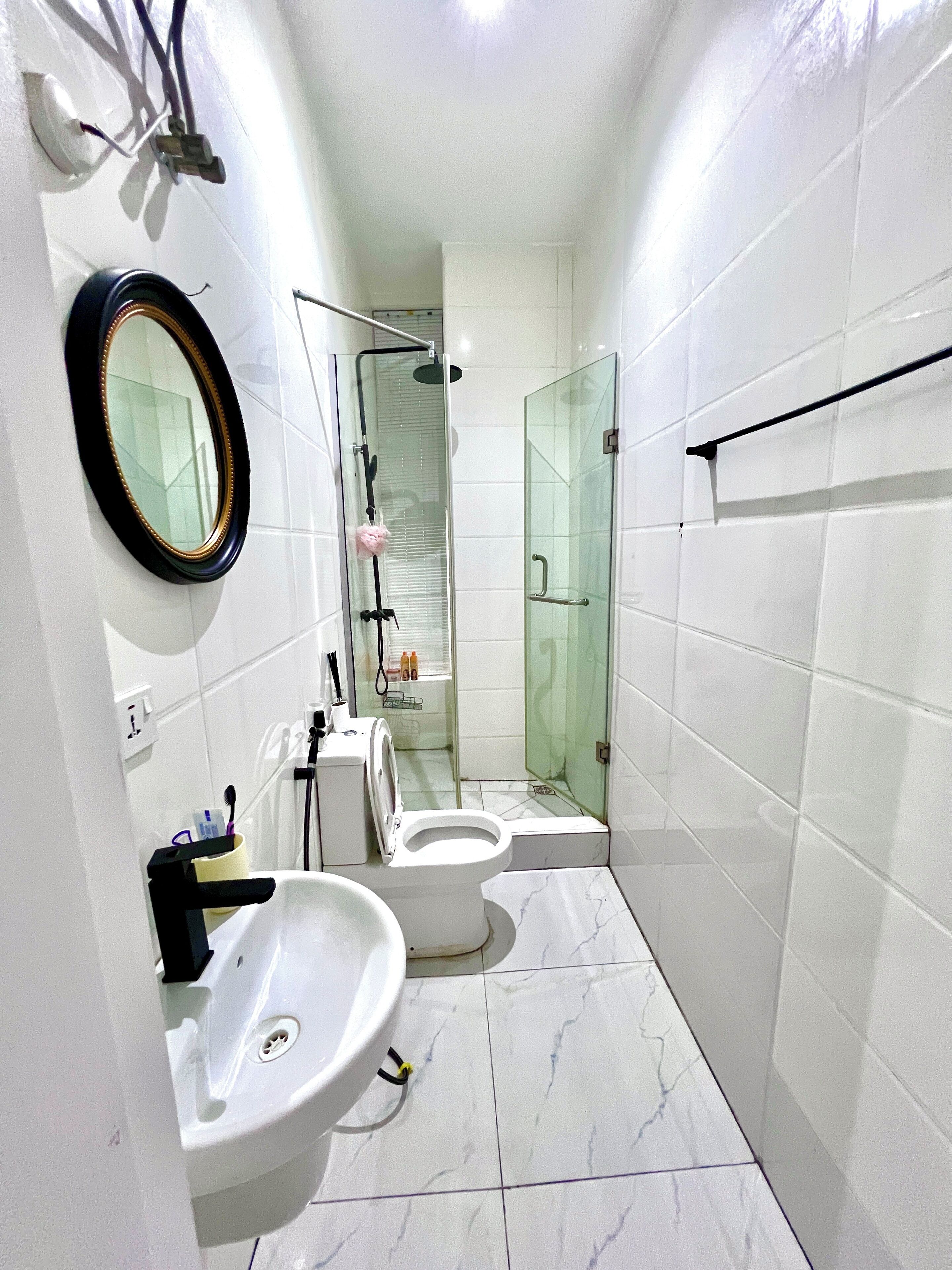 Une salle de bain moderne équipée de toilettes, d’un lavabo et d’une douche à parois en verre.