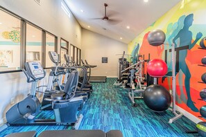 Een sportschool met trainingsapparatuur, een kleurrijke muurschildering en een vloerkleed met een patroon.