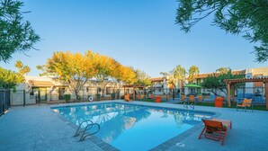 A swimming pool with a clear blue water surface, surrounded by a paved deck.