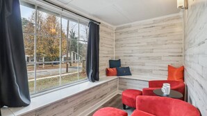Ett mysigt rum med ett stort fönster, träväggar och röda, klädda stolar.
