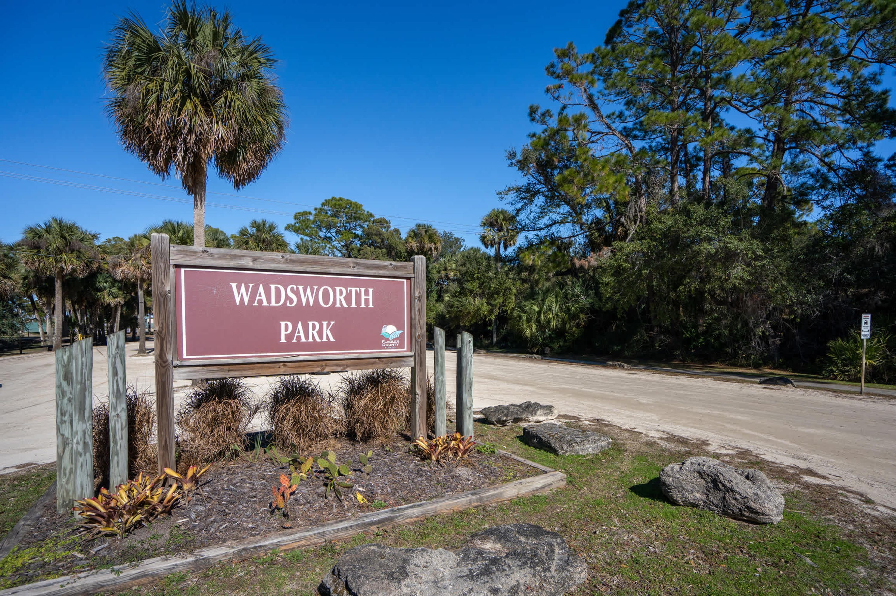Un panneau indiquant l’entrée du parc Wadsworth, avec une clôture en bois et des aménagements paysagers.