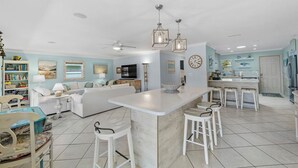 A spacious living area with a kitchen island, white furniture, and a ceiling fan. - Waterfront Retreat With Pool Tiki Bar Boat Dock (Palm Coast)
