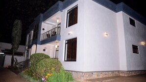A modern two-story house with a balcony, large windows, and a stone foundation.